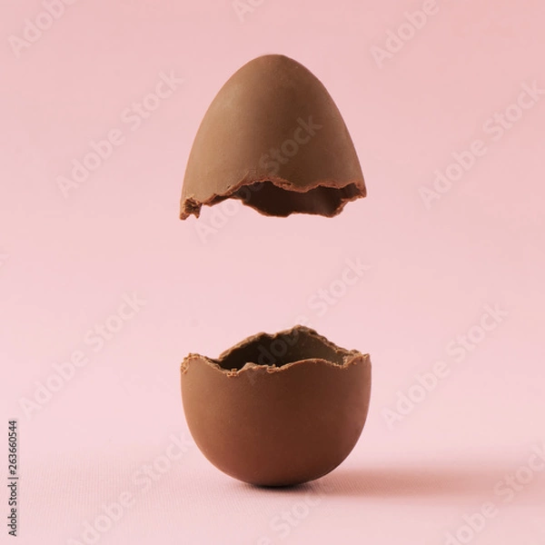 Fototapeta Chocolate Easter egg broken in half on pastel pink background with creative copy space. Minimal Easter holiday concept.