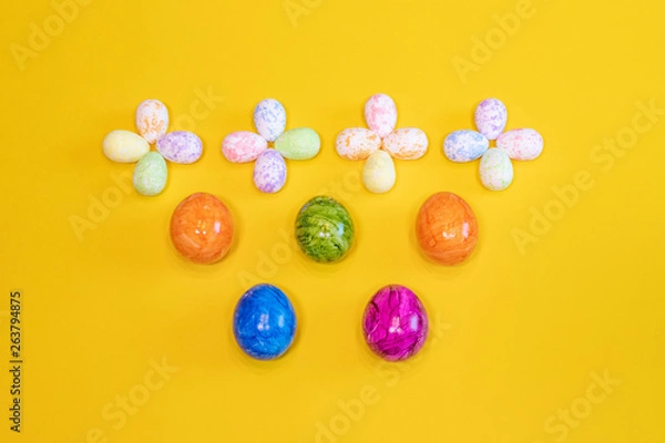 Fototapeta A lot of colorful Easter eggs on a yellow background. Top view, minimal Easter concept. Happy Easter card  with free, empty space.