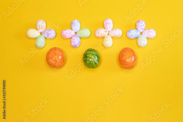 Fototapeta A lot of colorful Easter eggs on a yellow background. Top view, minimal Easter concept. Happy Easter card  with free, empty space.