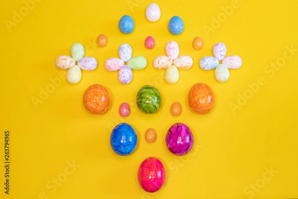 Fototapeta A lot of colorful Easter eggs on a yellow background. Top view, minimal Easter concept. Happy Easter card  with free, empty space.