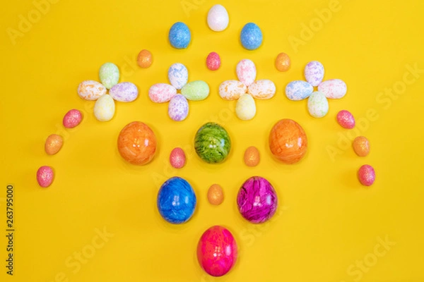 Fototapeta A lot of colorful Easter eggs on a yellow background. Top view, minimal Easter concept. Happy Easter card  with free, empty space.