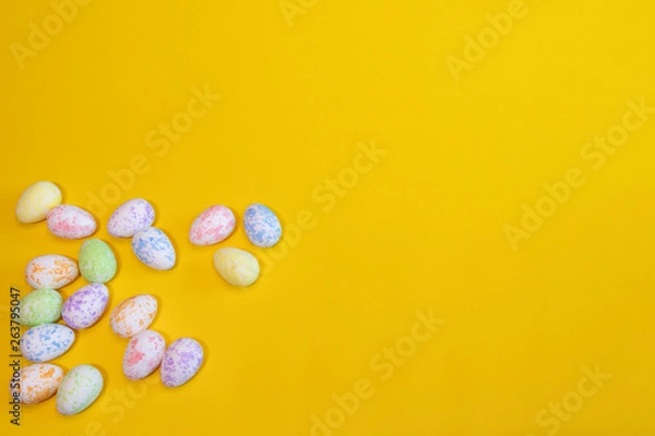 Fototapeta A lot of colorful Easter eggs on a yellow background. Top view, minimal Easter concept. Happy Easter card  with free, empty space.