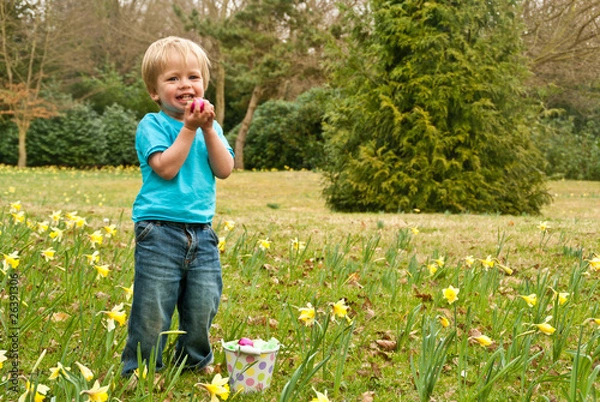 Fototapeta A toddler smiles while proudly holding an Easter egg