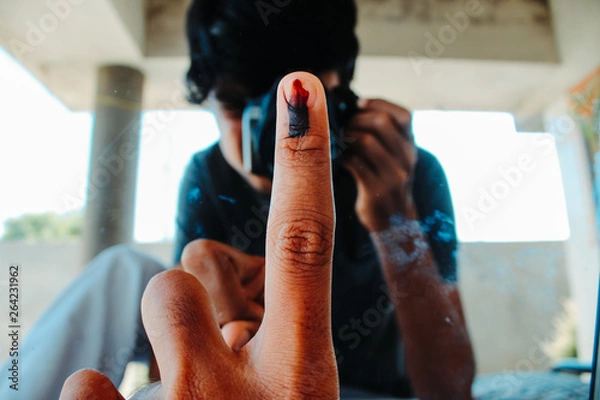Fototapeta Man photographing his index finger marked with ink in front of mirror and showing that he voted