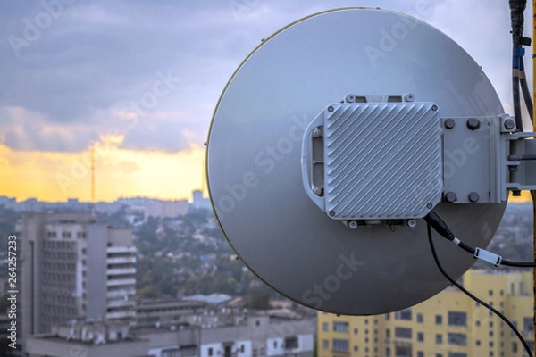 Fototapeta Telecommunication equipment for wireless data transmission is a close-up.Powerful round antenna is on the roof of the building. The base station of mobile communication works at height.