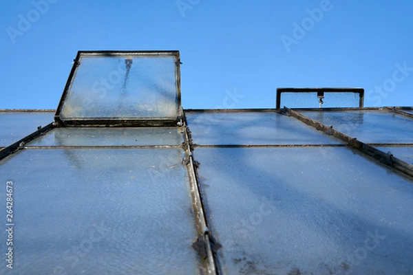 Fototapeta Garden shed closeup on a sunny day. You see the open windows for air flow and a clear sky.