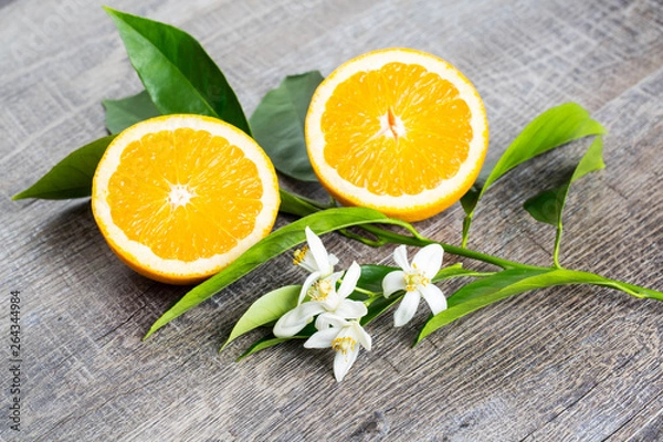 Obraz Juicy Orange cut in two parts and neroli, flowers of orange tree, on rustic wood background. The Orange blossom is the fragrant flower of the Citrus is used in perfume and tea, aphrodisiac.