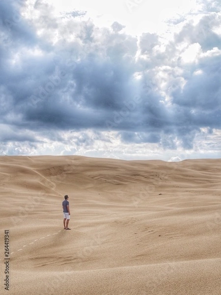 Fototapeta Looking out into the horizon and sand dunes whilst dark clouds linger overhead
