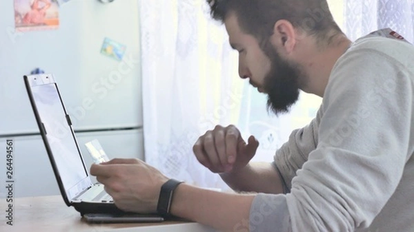 Obraz Entering credit card information into an on-line shopping site.