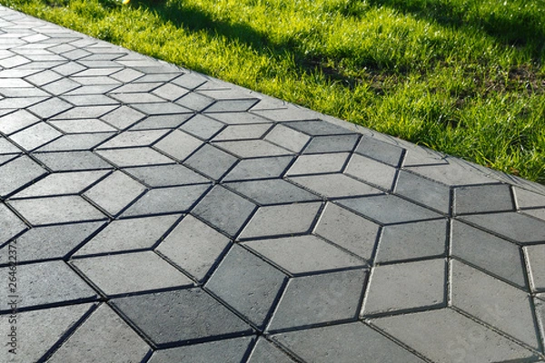 Fototapeta The footpath in the park is paved with diamond shaped concrete tiles.