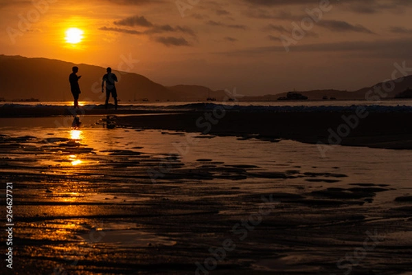 Obraz Silhouettes of people on the background of a golden dawn on the beach of Sanya, Hainan Island, China