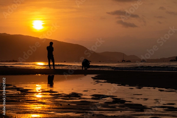 Obraz Silhouettes of people on the background of a golden dawn on the beach of Sanya, Hainan Island, China