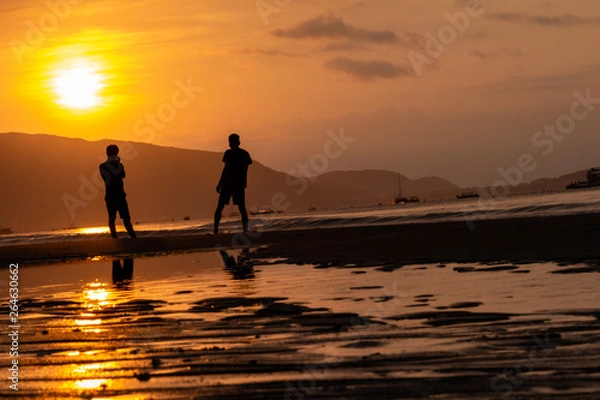 Obraz Silhouettes of people on the background of a golden dawn on the beach of Sanya, Hainan Island, China