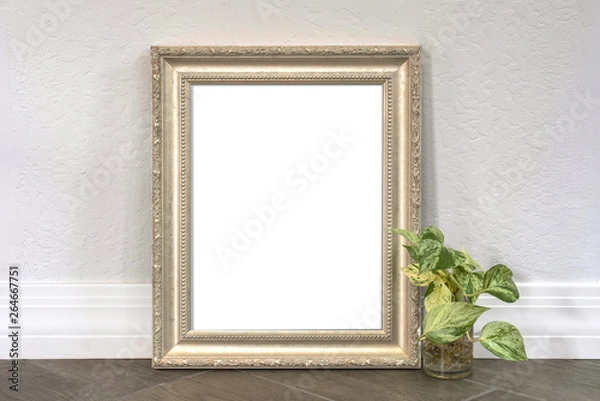 Fototapeta Silver pewter 8x10 picture frame with a philodendron plant on a wood textured tiled floor.  For mocking up photos and messages.