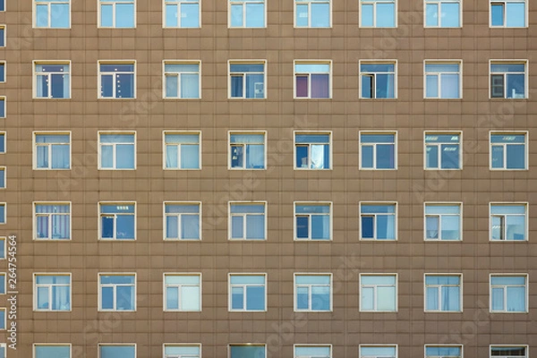 Fototapeta the gray facade of a high-rise multi-storey office building with white blue square windows