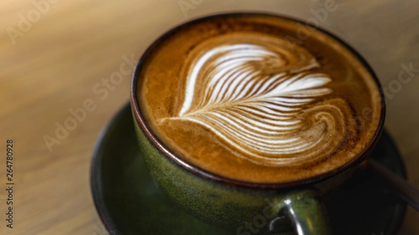 Obraz A beautiful dark cappuccino coffee created in a coffee shop in thailand, stoneware mug with a cappuccino with perfect Latte Art Served on a wooden table.