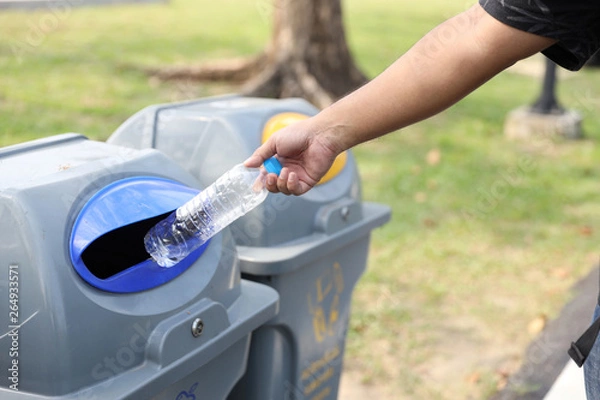 Fototapeta man hands throw empty plastic bottle into the garbage