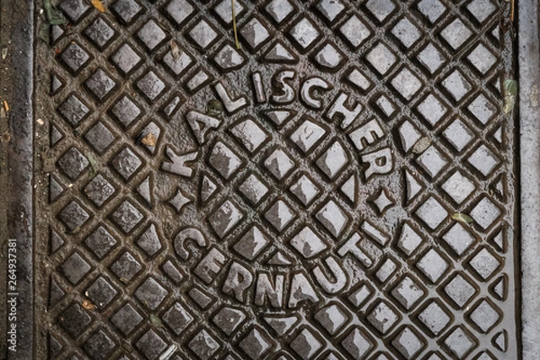 Fototapeta Close up of hatch in Chernivtsi, Ukraine. Metal rusty manhole cover. Translation: "Kalisher Chernivtsi" (name of the manufacturer's factory and name of the  city in Romanian)"
