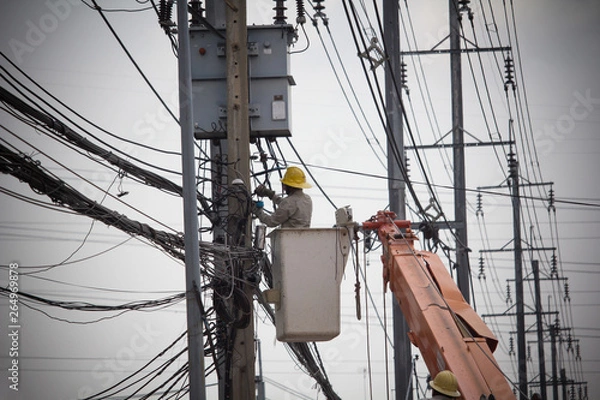 Fototapeta Electricians Wiring Cable repair services. Technician checking fixing broken electric wire on pole. Electricity power utility worker in crane truck bucket fixes high voltage power transmission line.