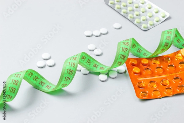 Fototapeta Diet pills. Ruler and pills on a gray background. Weight loss concept