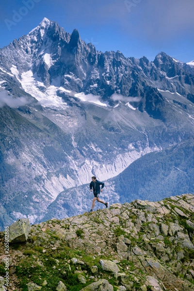 Fototapeta A trail runner, running along a trail in the high alpine mountains of the Mont Blanc range in France