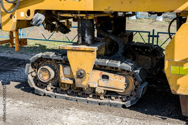 Fototapeta Road works. Dismantling of asphalt pavement. A fragment of a trimming unit-track.