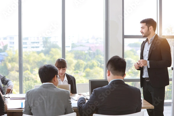 Fototapeta back view caucasian lecturer giving public presentation with company business graph result on white board in meeting room and multiethnic business people are paying attention 