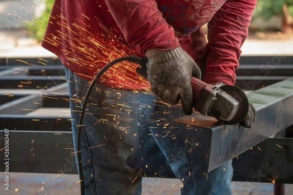 Fototapeta Close-up view of cutting steel shape, huge amount of sparks. Angle grinder sparks angle grinder cutting steel. Cutting steel with angle grinder. Worker cutting metal