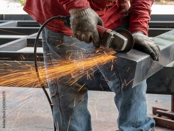 Fototapeta Close-up view of cutting steel shape, huge amount of sparks. Angle grinder sparks angle grinder cutting steel. Cutting steel with angle grinder. Worker cutting metal
