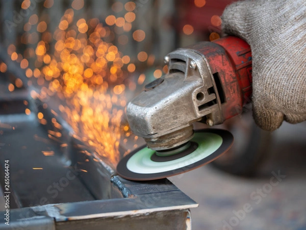Fototapeta Close-up view of cutting steel shape, huge amount of sparks. Angle grinder sparks angle grinder cutting steel. Cutting steel with angle grinder. Worker cutting metal