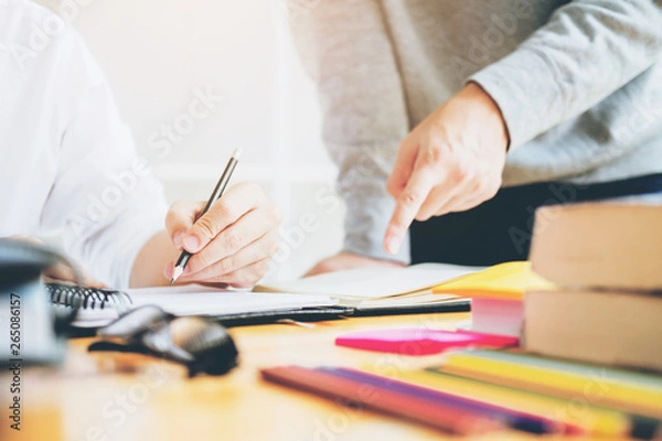Fototapeta High school or college students studying and reading together in library