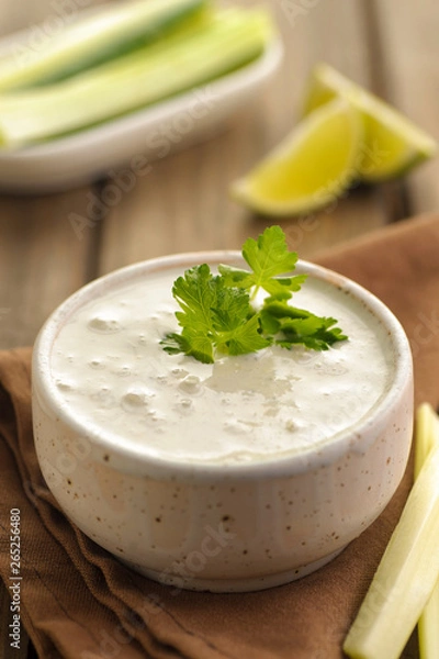 Fototapeta Blue cheese sauce in a portion with fresh vegetables and lime and green parsley. Wooden background and natural napkin. Close up and vertical view.