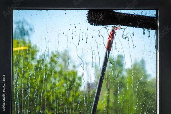 Obraz Window cleaning using telescopic water brush and wash system. Window cleaning from the outside with sky and trees in background 