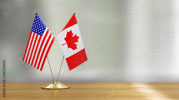 Obraz American and Canadian flag pair on a desk over defocused background 