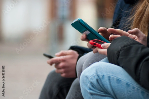 Obraz closeup of teenagers surfing on smartphone in the street
