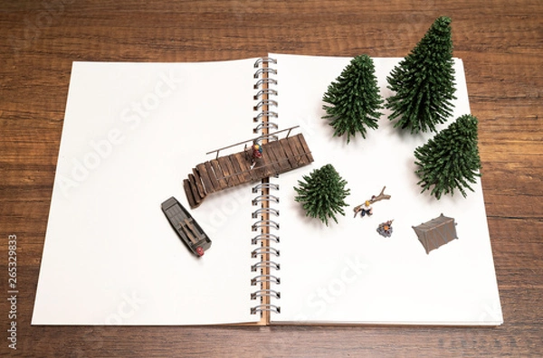 Fototapeta One miniature walking on bridge to boat and the other in camp fire on notebook