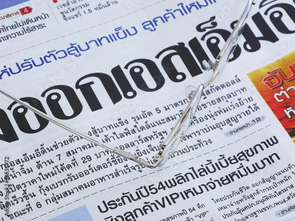 Fototapeta Close-up of Thai language newspaper and a pair of glasses.