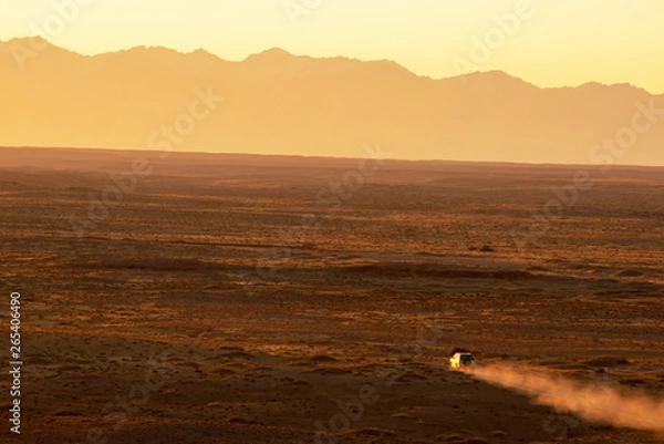 Fototapeta Suvs drive across the vast gobi desert in the early morning hours.