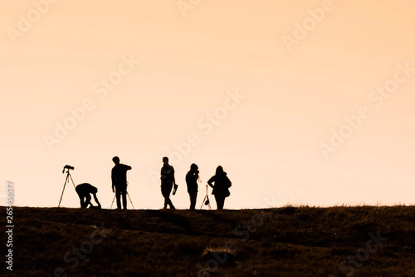 Fototapeta Silhouettes of hikers with backpacks enjoying sunset view from top of a mountain