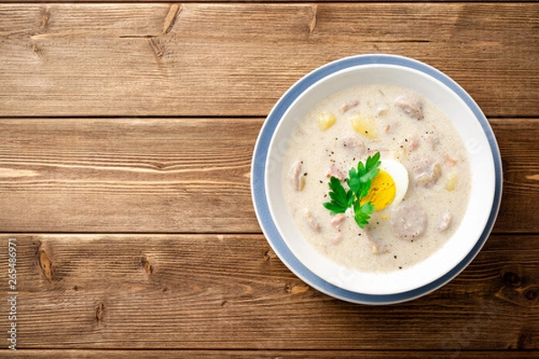 Fototapeta Traditional polish soup Zurek on wooden table. Top view. Copy space.