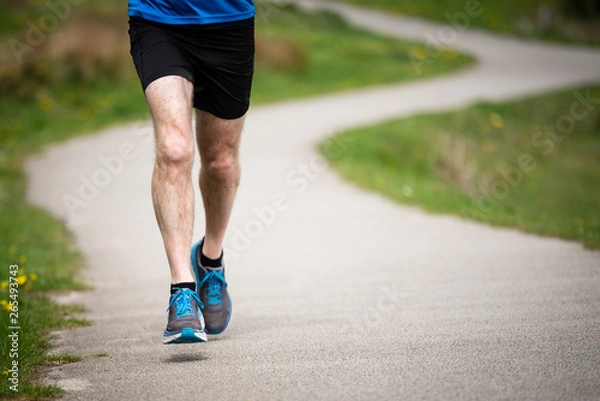 Fototapeta Senior man in 50s exercising and keeping fit by running in a park
