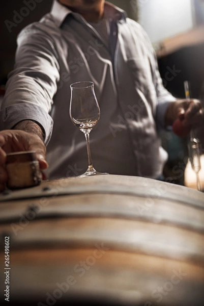 Fototapeta wooden barrel on a dark background, in a workshop, in an old room. production of barrels for cognac and wine, in a low key