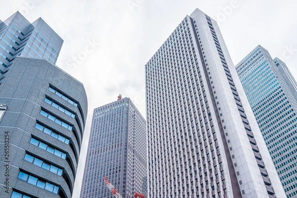 Fototapeta Shinjuku, Tokyo cityscape with low angle view of modern contemporary glass office skyscraper highrise apartment buildings and cloudy sky