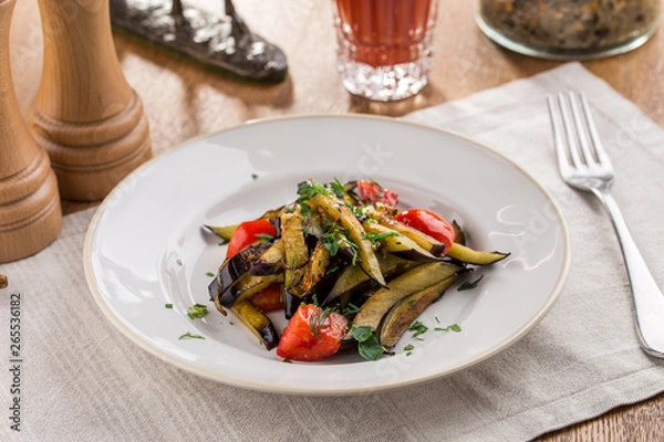 Fototapeta Grilled vegetables warm salad with eggplant and tomato with tomato juice on wooden table