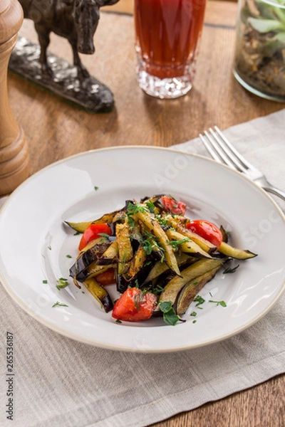 Fototapeta Grilled vegetables warm salad with eggplant and tomato with tomato juice on wooden table