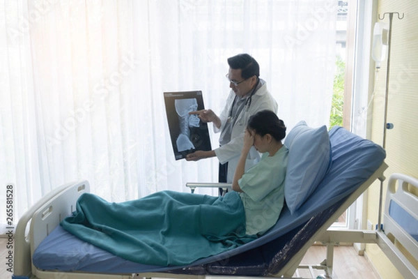 Obraz The senior male doctor talked about the patient's illness by explaining the X-ray film in the patient's bed.