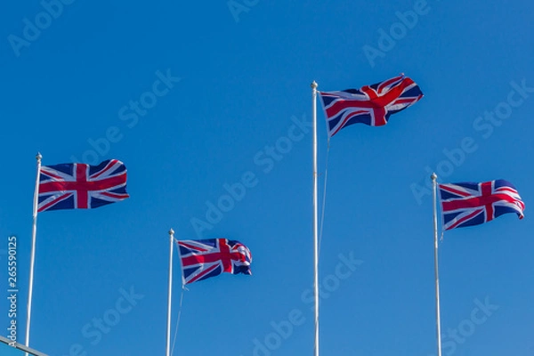 Obraz Four Union Jack, British flags on poles flying in the wind.