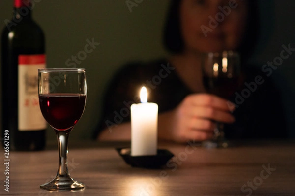 Fototapeta a glass of red wine on the background of a candlestick and a girl