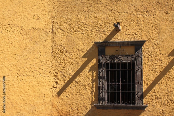 Fototapeta Ancient window in yellow wall with texture and shadow