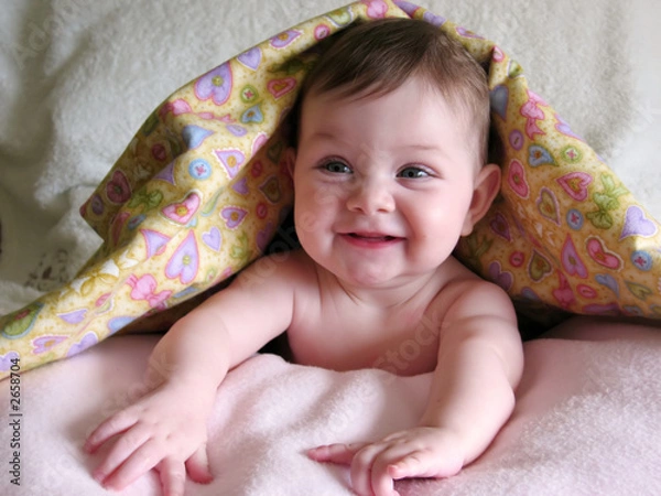 Fototapeta happy baby peeking out from under blanket